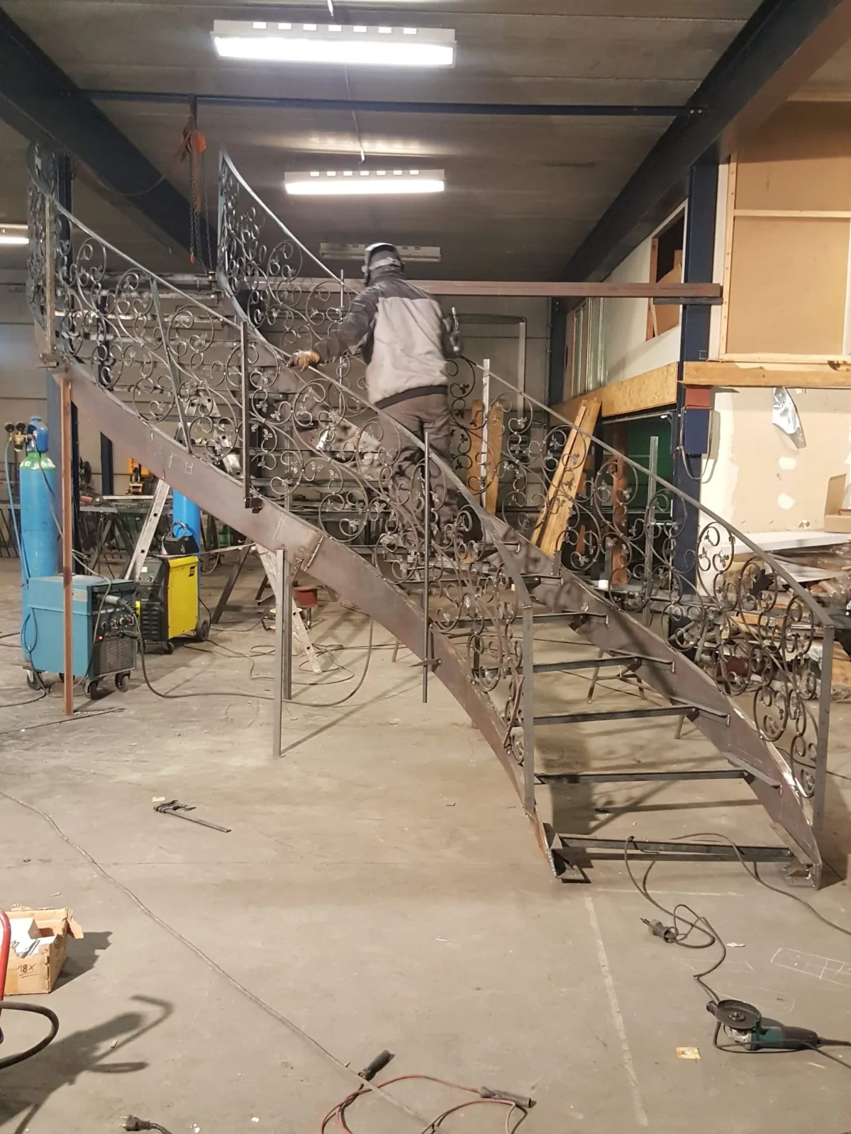 Ferronnier Lazaro Steel façonnant un escalier fer forgé, atelier métallerie sur mesure, Charleroi