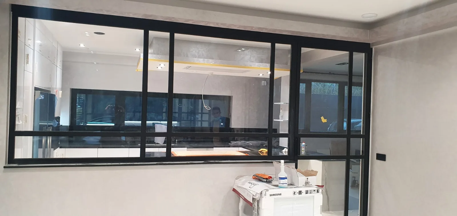 Verrière atelier en acier noir avec structure quadrillée séparant cuisine et salon, verrière sur mesure